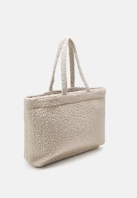 Beige woven tote bag with two short handles, featuring a textured, fluffy surface and rectangular shape, designed for casual use.