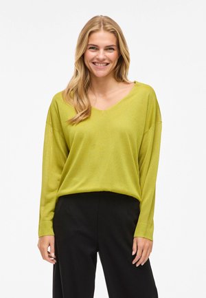 Grüner V-Ausschnitt-Pullover mit langen Ärmeln, aus leichtem Stoff; kombiniert mit schwarzen Hosen. Glatte Textur, lässige Passform.