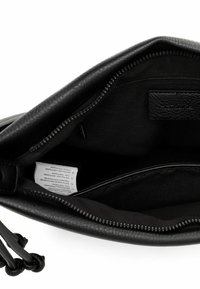 Interno di borsa in pelle nera, con chiusura a zip, fodera morbida e etichetta. Tasche interne per organizzazione.