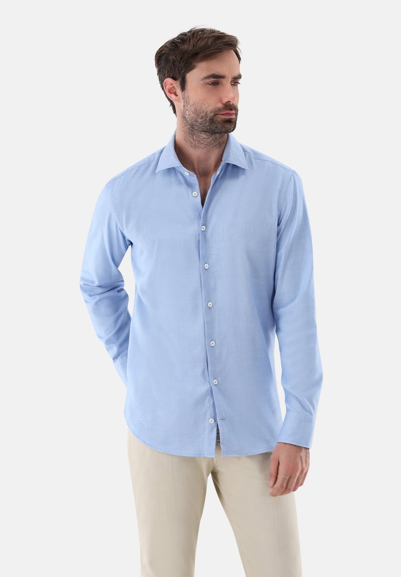 Camicia button-up azzurro chiaro con colletto classico, maniche lunghe e texture liscia. Presenta bottoni bianchi e un orlo curvo.