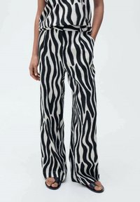 Črno-bela široka hlače z zebra vzorcem z ohlapnim krojem. Narejene iz lahkega materiala, z stranskimi žepi in sproščenim dizajnom.