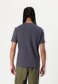 Pilkas medvilnės marškinėliai su apvaliu kaklu ir trumpomis rankovėmis. Lygus paviršius, pritaikyta išvaizda, jokių matomų raštų, rodoma iš nugaros.