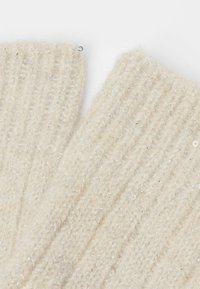 Gestrickte cremfarbene fingerlose Handschuhe aus weicher, strukturiertem Garn mit glänzenden silbernen Fäden, ausgestattet mit einem gerippten Design und offenen Fingerspitzen.