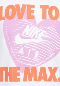 Hvit t-skjorte med fet oransje tekst "LOVE TO" og rosa hjerte med Nike-logo og "AIR" i hvitt, alt på et glatt bomullsstoff.