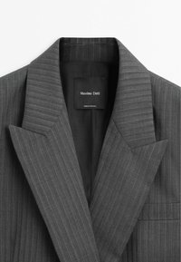 Donkergrijze krijtstreeppatroon blazer met kraag en revers met Massimo Dutti-label aan de binnenkant, gemaakt in Portugal.