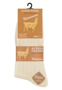 Calzini in lana di alpaca di un morbido color crema, con una texture a coste e un'etichetta rettangolare che presenta illustrazioni e dettagli sul prodotto.