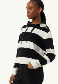 Striped hoodie in black and white, with a drawstring hood, long sleeves, and a soft texture. Features side pockets and a relaxed fit.