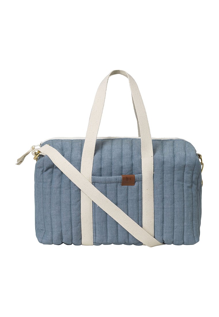 Sac en tissu matelassé bleu avec des poignées crème et une bandoulière réglable, comprenant une poche avant et un accent en cuir près de la fermeture éclair.