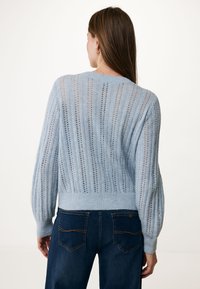 Ljusblå stickad tröja med lös passform, med intrikata vertikala ränder och hålstickad textur. Ribbad nederkant och ballongsärmar.