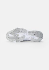 Semelle de basket blanche et grise avec des motifs de bande de roulement et de petits trous circulaires visibles sur un fond blanc uni.