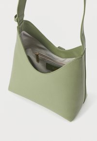 Ανοιχτό πράσινο δερμάτινο τσαντάκι ώμου με υφή στην επιφάνεια, φαρδιά λουράκι και ορατή εσωτερική τσέπη με φερμουάρ και υφασμάτινη επένδυση.