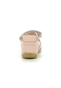 Sandal in pelle rosa con una fascia in Velcro, lati aperti, supporto per il tallone posteriore e una suola in beige chiaro con texture. Presenta il logo 'Kickers' sulla suola.