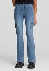 Jeansy cargo z dżinsu w kolorze niebieskim, rozszerzane, z dwiema bocznymi kieszeniami, szlufkami na pasek i średnim stanem, charakteryzujące się teksturowanym wykończeniem oraz klasycznym przeszyciem.