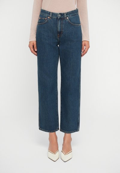 Højtaljede, brede ben blå denim jeans med fem lommestil, kobbernitter og en glat tekstur. Afsluttet med en kant, der når midt på anklerne.