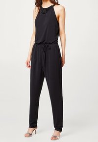 Black sleeveless jumpsuit with a fitted waist and loose legs. Features a textured neckline with embellishments, made from a smooth fabric.