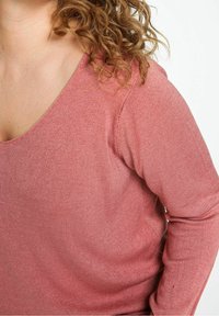 Maglione a maniche lunghe con scollo a V in tessuto morbido e testurizzato. Il colore è rosa polveroso con una delicata lavorazione a costine. Presenta una vestibilità comoda intorno alle spalle.
