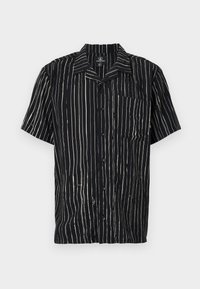 Short-sleeve shirt in black fabric featuring vertical white stripes, a pocket on the left chest, and a collar with a relaxed fit.
