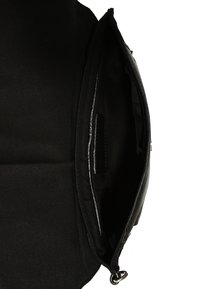 Sac à main noir ouvert montrant un compartiment principal avec une doublure en tissu et une poche intérieure, sur fond blanc.