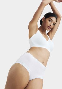 Witte naadloze beha met een V-halsontwerp, gecombineerd met witte slipjes met hoge taille. Gladde textuur, minimalistische stijl en zacht materiaal.