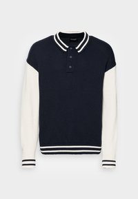 Jersey de punto con cuerpo en azul marino, mangas en crema y cuello a rayas. Tapeta con tres botones y puños acanalados con rayas en azul y blanco.