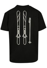 Black t-shirt featuring a white outline design of ski equipment—two skis and a ski pole—on the back. Short sleeves, relaxed fit.