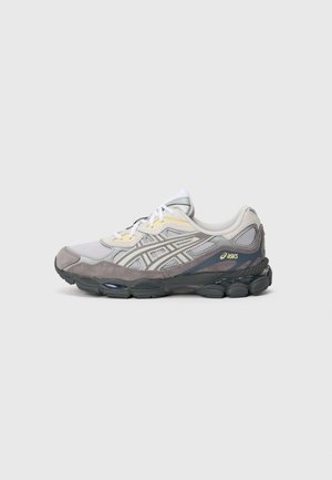 Vue de côté d'une chaussure de course ASICS grise et blanche avec des détails en maille et en cuir suédé, des lacets blancs et une semelle noire rembourrée.