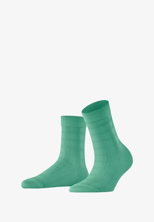 Chaussettes en coton vert avec un motif à carreaux, des bords côtelés et une texture lisse. Design de longueur au niveau de la cheville avec des zones de orteil et de talon renforcées.