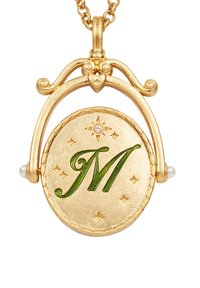 Collana con pendente in oro che presenta una "M" verde con accenti a stella, incorniciata da un arco decorativo e due piccole perle su entrambi i lati.