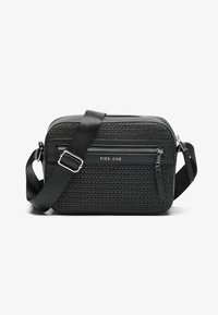 Sac bandoulière noir avec un devant en tissu texturé, des accents en cuir lisse, une sangle ajustable et des compartiments zippés. Logo sur le devant.