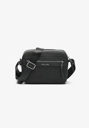 Black crossbody bag with textured fabric front, smooth leather accents, adjustable strap, and zippered compartments. Logo on front.