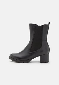 Bota de cuero negra a media pantorrilla con paneles laterales elásticos, tacón cuadrado y tira de agarre sobre un fondo blanco, vista de lado.