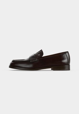 Tumepruun nahast penny loafer madala kand ja õmblustega pealmisel osal, näidatud küljelt tavalise heleda taustaga.