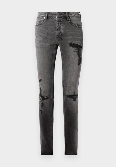 Schwarze Denim-Jeans mit Rissdetails, schlankem Schnitt, fünf Taschen und klassischem Reißverschluss. Abgetragenes Aussehen mit verblassten Stellen.