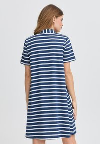 Abito a maniche corte di colore blu navy con strisce orizzontali bianche, caratterizzato da un collo a camicia e una silhouette A-line rilassata. Tessuto morbido.