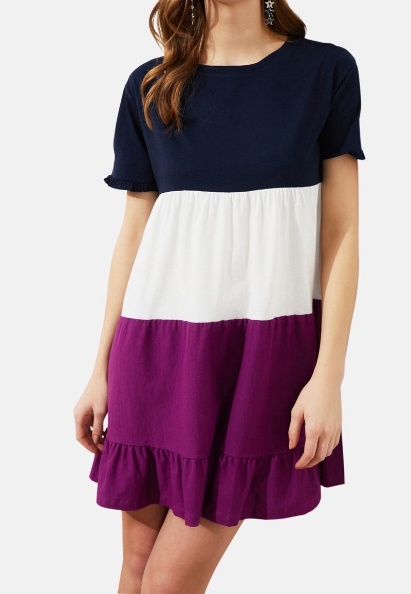 Robe à manches courtes avec un haut bleu marine, un milieu blanc et une jupe évasée violette, ornée d'un ourlet à volants. Fabriquée en tissu léger mélangé en coton.