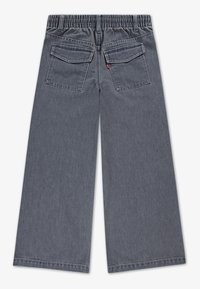 Pilki platūs džinsai su elastine juosta ir dviem užnugario kišenėmis, pateikti iš nugaros pusės.