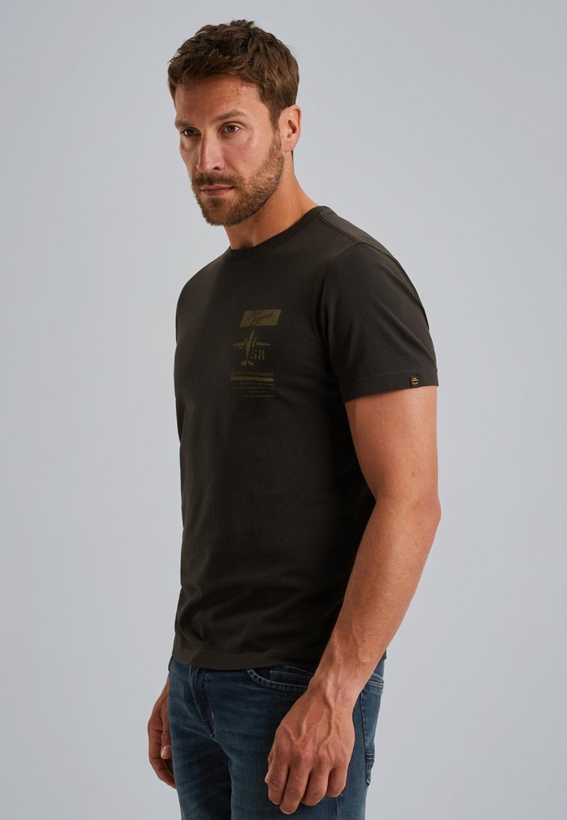 Camiseta de algodón verde oscuro con mangas cortas, que presenta un sutil estampado gráfico en la parte frontal y una pequeña etiqueta con el logo en el dobladillo.