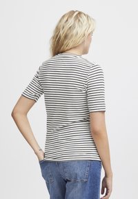 Gestreepte t-shirt met korte mouwen in crème met marineblauwe horizontale strepen. Zacht katoenen materiaal, aangesloten ontwerp, ronde halslijn en een achteraanzicht.