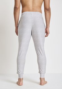 Lichtgrijze joggerbroek gemaakt van zacht, rekbaar materiaal, met een aansluitend ontwerp, elastische tailleband en enkelsupport.