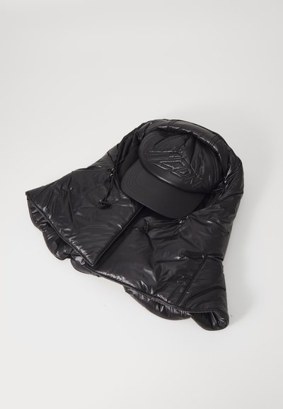 Giacca nera imbottita con cappuccio, caratterizzata da una texture lucida e chiusura con zip, abbinata a un cappellino nero con logo in rilievo sulla parte anteriore.