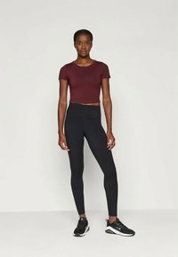 Burgunder crop-top, høyt liv svarte leggings og svarte treningssko. Glatt stoff med en tettsittende design uten synlige mønstre eller akzenter.