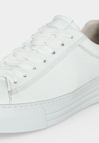 Λευκό δερμάτινο sneaker χαμηλής κορυφής με λευκά κορδόνια, ορατή ραφή, υφή στη λαστιχένια σόλα και επενδεδυμένη εσωτερική επένδυση.