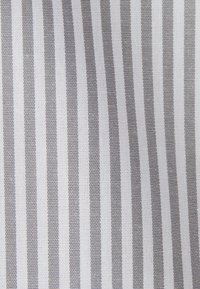 Close-up van stof met verticale witte en lichtgrijze strepen die de geweven textuur en het afwisselende patroon benadrukken.