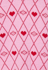 Pletená látka s růžovým pozadím a opakujícím se diamantovým vzorem v červené barvě. Mezi tím se nacházejí srdce a stylizované motivy cukrovinek.