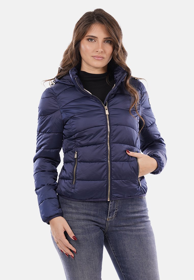 Giubbotto puffer blu navy con zip frontale, tasche laterali e texture trapuntata. Presenta un cappuccio e un design aderente per calore e comfort.