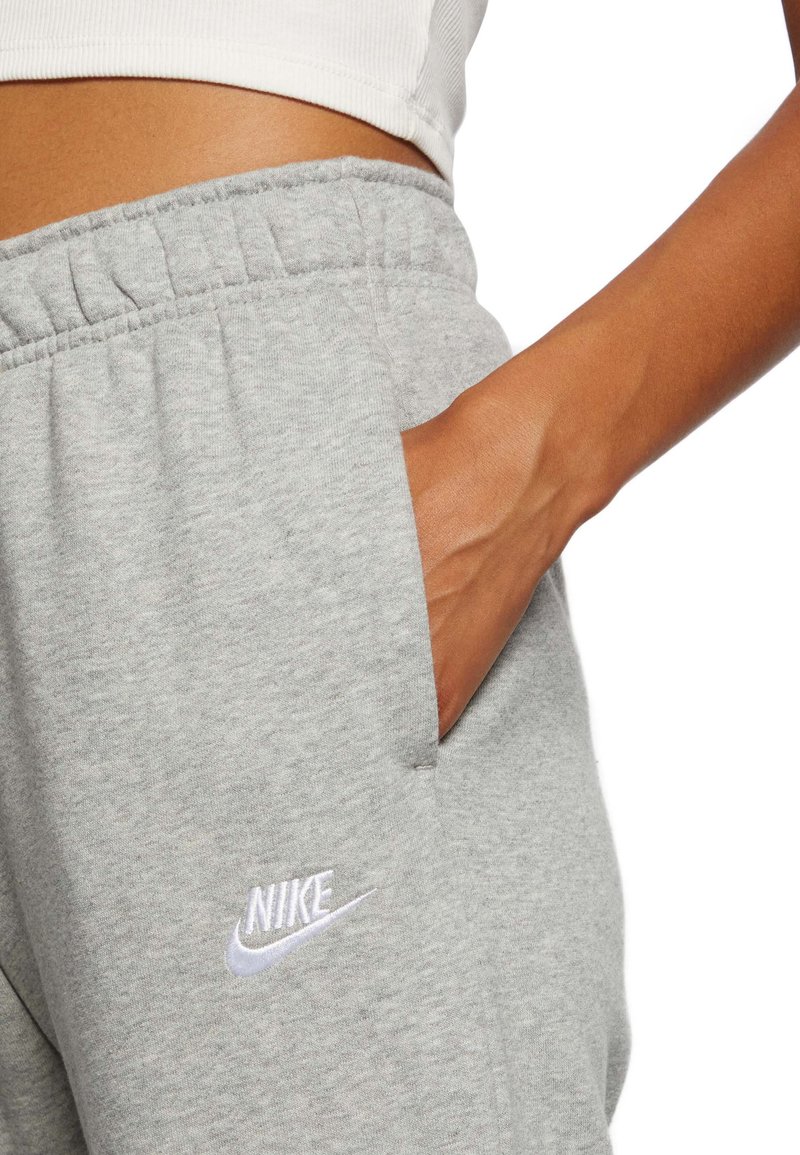 Des joggeurs en coton gris présentent une taille élastique, des poches latérales et un logo Nike brodé en blanc sur la hanche gauche.
