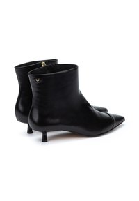Botas de tobillo de cuero negro con puntera puntiaguda, tacón bajo tipo kitten, textura suave y un pequeño acento dorado en el lado.