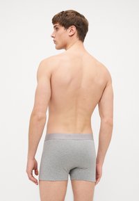 Shorts en coton gris avec une ceinture gris clair portant le texte "GAP". Le design est simple et ajusté avec une texture lisse.