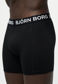 Κοντινό πλάνο ενός ατόμου που φοράει μαύρα μπόξερ Björn Borg με ελαστική ζώνη μέσης με λογότυπο.