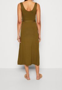 Olivově zelené, bezramínkové maxi šaty s přiléhavým živůtkem a páskem v oblasti pasu. Měkká tkanina, hladká textura a rozšířená sukně.